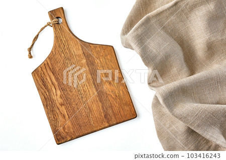 A beige wooden cutting board and a rough beige linen napkin on a A beige wooden cutting board and a rough beige linen napkin on a 103416243