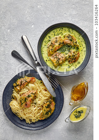 Fried poultry chicken baked with garlic and herbs in milk cream and noodles. Fried chicken with spaghetti on dark plates on a gray concrete table 103416264