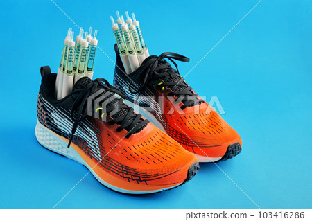 Orange sneakers with insulin syringe pens isolated on a blue background on a blue background Orange sneakers with insulin syringe pens isolated on a blue background on a blue background 103416286