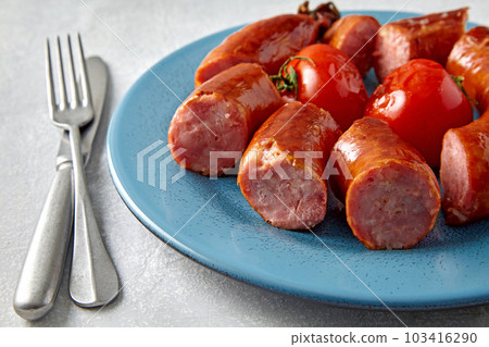 lled pork sausage cut into pieces in a blue plate with tomatoes and cutlery on a light gray stone background lled pork sausage cut into pieces in a blue plate with tomatoes and cutlery on a light gray stone background 103416290