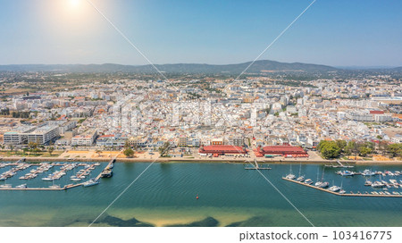 Aerial view of Portuguese fishing tourist town of Olhao with a view the Ria Formosa Marine Park. Sea port for yachts and Sun over the mountains Aerial view of Portuguese fishing tourist town of Olhao with a view the Ria Formosa Marine Park. Sea port for yachts and Sun over the mountains 103416775