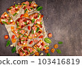 Cut into slices delicious fresh pizza with sausage and cheese on a dark background. Top view with copy space for text. Pizza on the black concrete table. flat lay 103416819