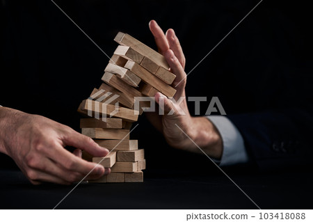 Plan and strategy in business, Risk To Make Business Growth Concept With Wooden Blocks, hand of man has piling up and stacking a wooden block. Plan and strategy in business, Risk To Make Business Growth Concept With Wooden Blocks, hand of man has piling up and stacking a wooden block. 103418088
