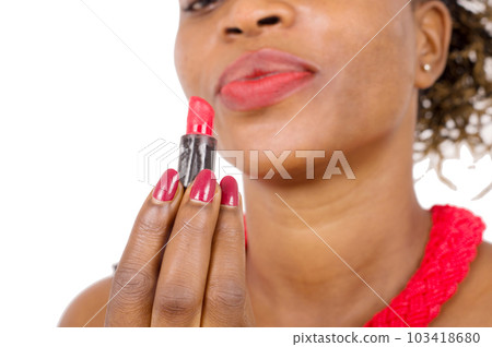 Closeup of beautiful African woman looking at her lipstick. 103418680