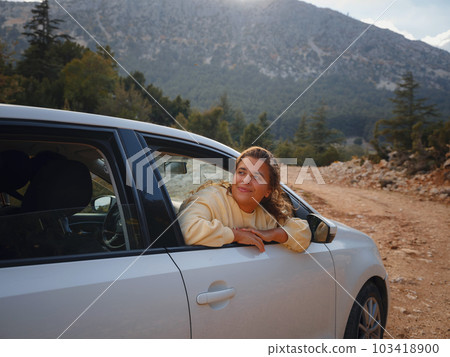Woman on road trip traveling by rental car 103418900
