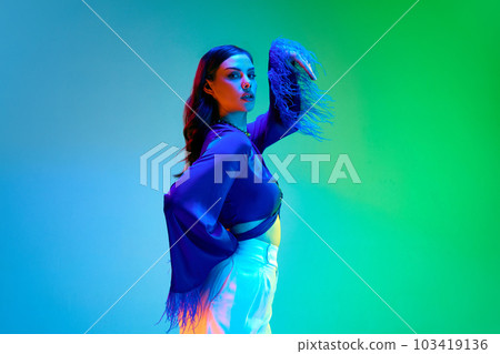 Beautiful brunette girl with bright make-up wearing blue silk blouse with feathers over gradient neon background. Glamour comfort home dress, luxury pajama Beautiful brunette girl with bright make-up wearing blue silk blouse with feathers over gradient neon background. Glamour comfort home dress, luxury pajama 103419136