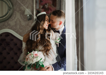 Beautiful young wedding couple posing with bouquet of flowers in hands 103420143