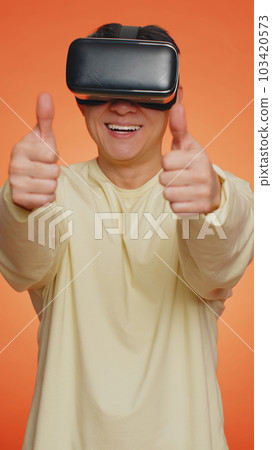 Handsome man using virtual reality headset helmet to play simulation game app watching video content Handsome man using virtual reality headset helmet to play simulation game app watching video content 103420573