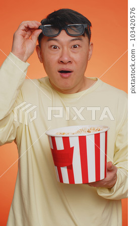 Excited man in 3D glasses eating popcorn and watching interesting tv serial, sport game film movie Excited man in 3D glasses eating popcorn and watching interesting tv serial, sport game film movie 103420576
