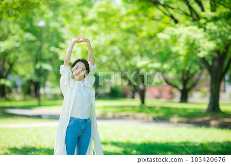 A woman stretching in a fresh green park 103420676