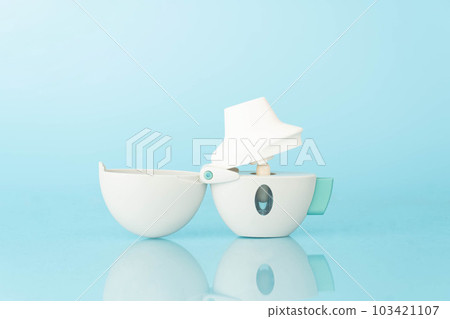 Asthma and COPD concept. Tiotropium bromide inhaler with reflection on light blue background. Pharmaceutical device of bronchodilator for lung inflammation treatment and prevent asthma attack. 103421107