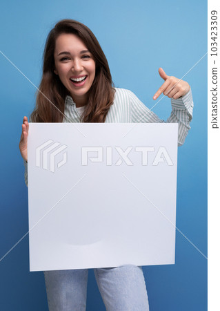 pretty brunette young business woman in a shirt demonstrates a white poster with a mockup 103423309