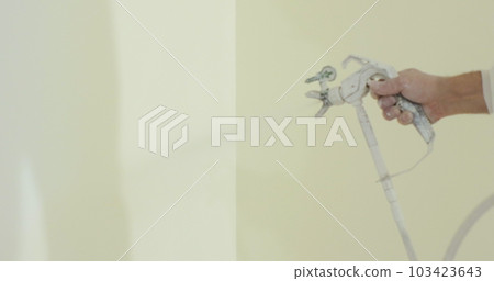 Close up of man painter paints the walls with paint spray gun. Airless spray painting. Close up of man painter paints the walls with paint spray gun. Airless spray painting. 103423643