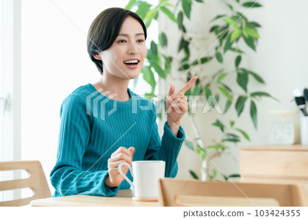 Woman relaxing with a hot drink in the living room Woman relaxing with a hot drink in the living room 103424355