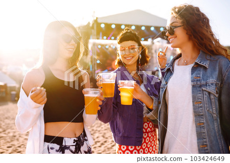 Girlfriends drinking beer and having fun at music festival. Friendship and celebration. Beach party. Girlfriends drinking beer and having fun at music festival. Friendship and celebration. Beach party. 103424649