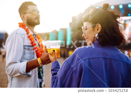 Young and cheerful couple at music festival. Happy friends drinking beer and having fun. 103425258