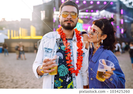 Young and cheerful couple at music festival. Happy friends drinking beer and having fun. 103425260