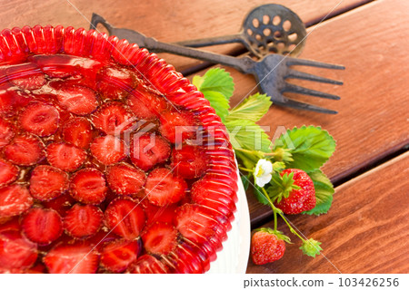 Village life. Summer period. Cake with strawberries and whipped cream decorated with leaves on wooden background Village life. Summer period. Cake with strawberries and whipped cream decorated with leaves on wooden background 103426256