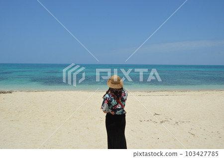 A woman photographing the blue sky, the horizon and the sandy beach 103427785