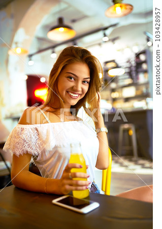 beautiful girl with lovely smile sitting in cafe drinking lemonade and using phone. Excellent summer beautiful girl with lovely smile sitting in cafe drinking lemonade and using phone. Excellent summer 103428957
