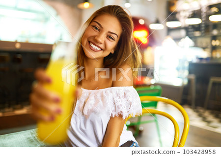 beautiful girl with lovely smile sitting in cafe drinking lemonade and using phone. Excellent summer beautiful girl with lovely smile sitting in cafe drinking lemonade and using phone. Excellent summer 103428958