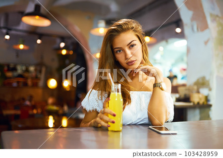 beautiful girl with lovely smile sitting in cafe drinking lemonade and using phone. Excellent summer beautiful girl with lovely smile sitting in cafe drinking lemonade and using phone. Excellent summer 103428959