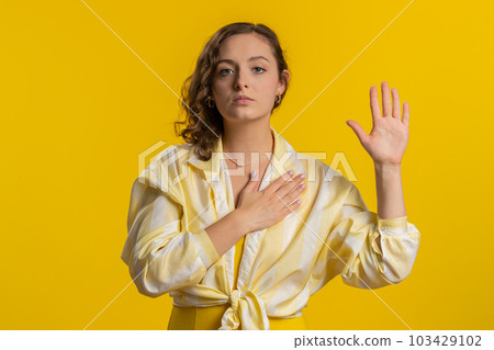 Woman raising hand to take oath, promising to be honest and to tell truth, keeping hand on chest 103429102