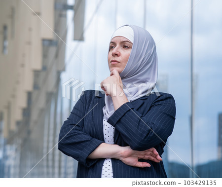 Portrait of pensive business woman in hijab and suit outdoors.  103429135