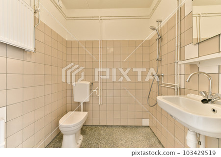 a small bathroom with tiled walls and flooring, including a white toilet in the corner next to the sink 103429519