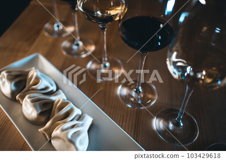 Georgian khinkali dumplings with red and white wine in glasses on wooden table Georgian khinkali dumplings with red and white wine in glasses on wooden table 103429618