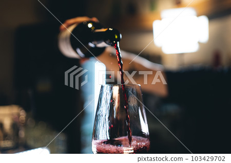 bartender pouring red luxury wine in wineglass, closeup macro bartender pouring red luxury wine in wineglass, closeup macro 103429702