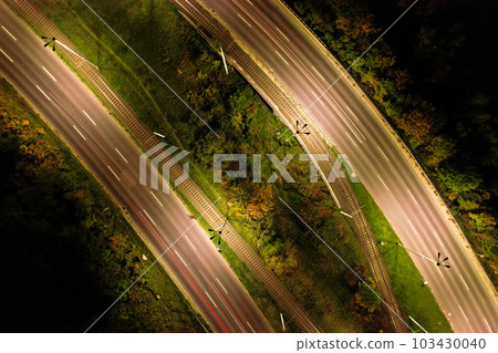 Top down view to road. Romantic night aerial photo of cars traveling. The light on the road at night in city. Background scenic road drone view. Tram railways Top down view to road. Romantic night aerial photo of cars traveling. The light on the road at night in city. Background scenic road drone view. Tram railways 103430040