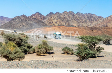 Trucks in desert landscape with mountains in the background, near Al Ula, Saudi Arabia 103430122