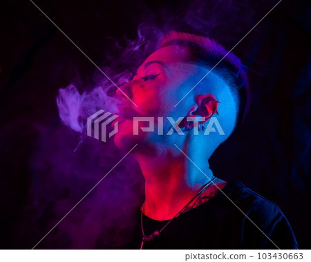 Profile Asian woman with short haircut smoking in neon light. 103430663