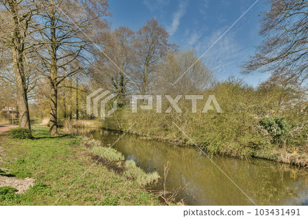 a small river in the middle of a park with trees on both sides and blue skies overhead above, as seen from an angle a small river in the middle of a park with trees on both sides and blue skies overhead above, as seen from an angle 103431491