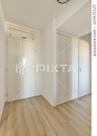 an empty room with wood floors and white doors on either side, there is a clock hanging above the door 103431527