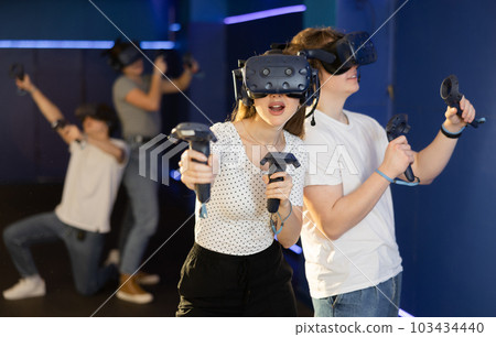 Young guy and girl in vr headset stand shoulder to shoulder interacting with digital interface Young guy and girl in vr headset stand shoulder to shoulder interacting with digital interface 103434440