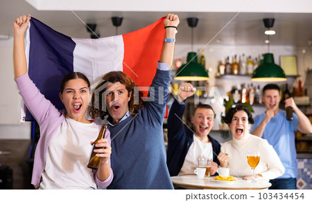 Joyful friends with France flag celebrating victory of favorite team in bar Joyful friends with France flag celebrating victory of favorite team in bar 103434454