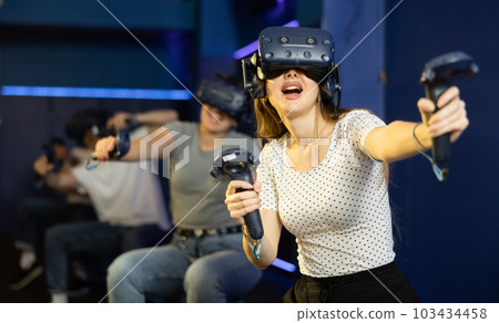 Happy woman is fascinated by movie in virtual reality glasses in room 103434458