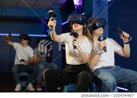friends in helmets and with joysticks are sitting playing 3d action game. entertainment club friends in helmets and with joysticks are sitting playing 3d action game. entertainment club 103434467