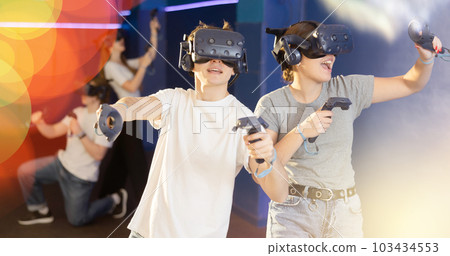 Young guy and girl in vr headset stand shoulder to shoulder interacting with digital interface 103434553