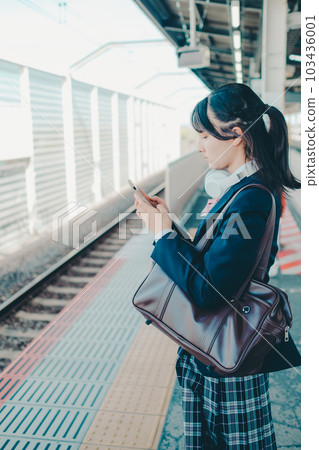 一個拿著智能手機站著的女高中生 103436001