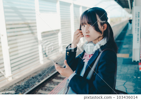 一個拿著智能手機站著的女高中生 103436014