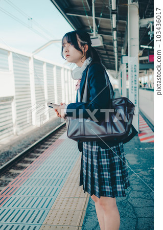 一個拿著智能手機站著的女高中生 103436017