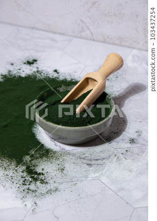Blue-green algae Chlorella and spirulina powder in bowl with wooden spoon. Super powder. Natural supplement of algae. Detox superfood drink cocktail. Food supplement source of protein and beta 103437254