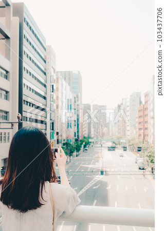 A woman holding a smartphone in the city A woman holding a smartphone in the city 103437706