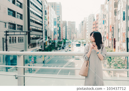 一個在城市裡拿著智能手機的女人 一個在城市裡拿著智能手機的女人 103437712