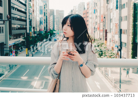 一個在城市裡拿著智能手機的女人 一個在城市裡拿著智能手機的女人 103437713