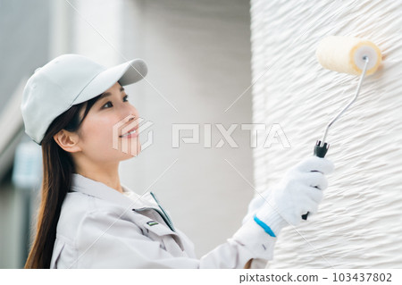 在外牆上塗塗層劑的年輕婦女 在外牆上塗塗層劑的年輕婦女 103437802