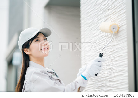 Young woman of renovation contractor to paint the exterior wall Young woman of renovation contractor to paint the exterior wall 103437803